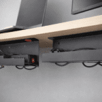 Bandeja slim bajo escritorio con regleta y cables ordenados; opción adhesiva y atornillada para home office.